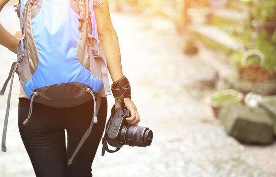 Rückenansicht von Frau mit Rucksack und Fotoapparat