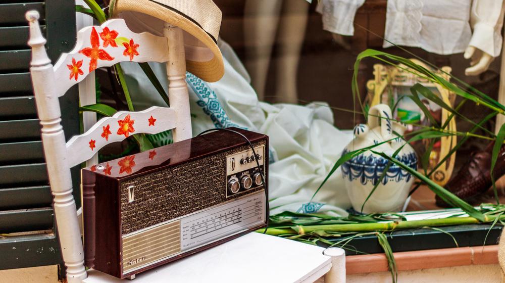 Kubanisches Stillleben mit einem weißen Sessel, ein altes Radiogerät darauf und ein Herrenstrohut.