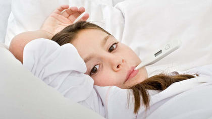 Krankes Mädchen mit Fiebermesser im Mund im Bett liegend