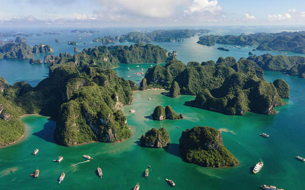 Vogelperspektive auf das Meer mit vereinzelten Inseln und Booten in Vietnam