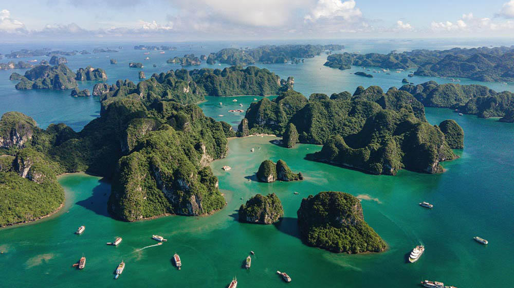 Vogelperspektive auf das Meer mit vereinzelten Inseln und Booten in Vietnam