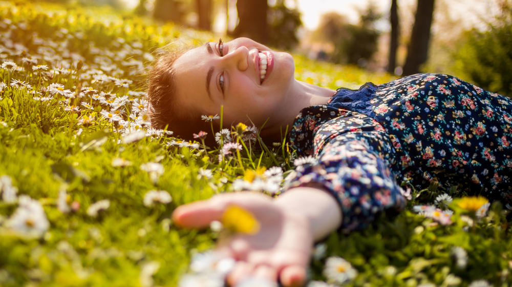 Nahaufnahme einer jungen Frau, die auf einer sonnenbestrahlten Wiese liegt.