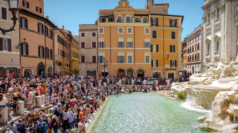 On the right the Trevi Fountain in Rome, on the left crowds of people standing very close together.