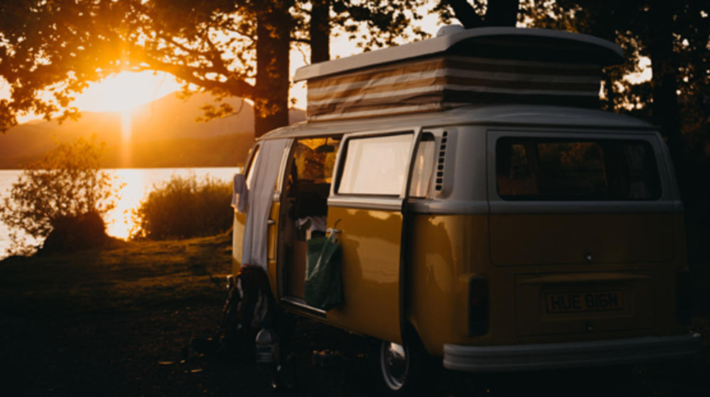 Old VW camper van, parked on a lake at sunset.