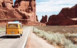 Old VW bus on a road through barren terrain, desert.