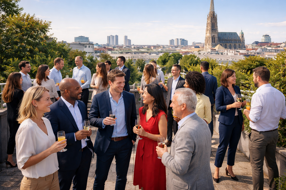 Eine Gruppe von Menschen auf einer Dachterrasse mit Blick über Wien