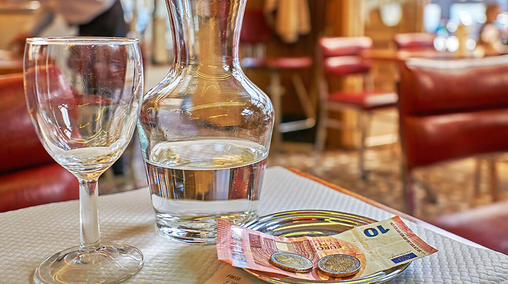 Cash including a tip on a bill tray in a café