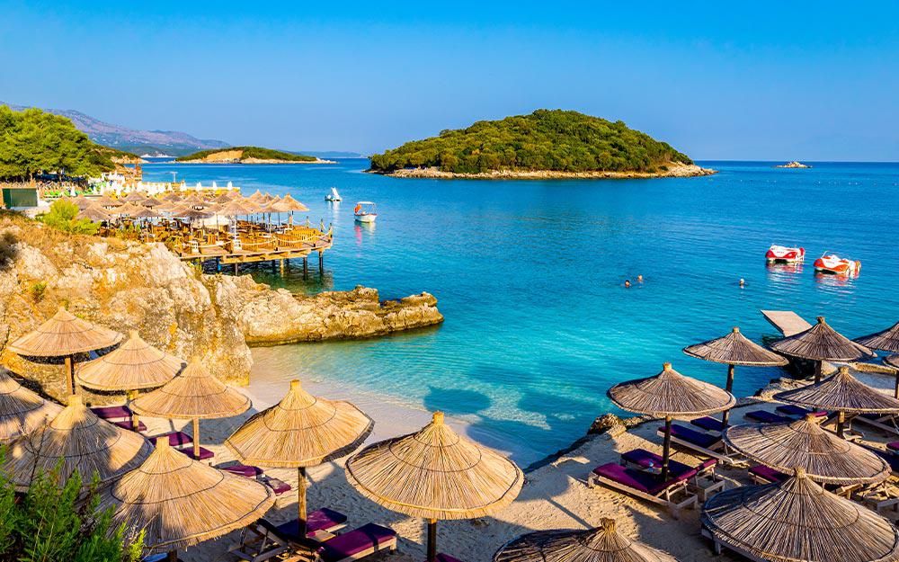 Strand mit Sonnenschirmen und Sonnenliegen an der Albanischen Riviera