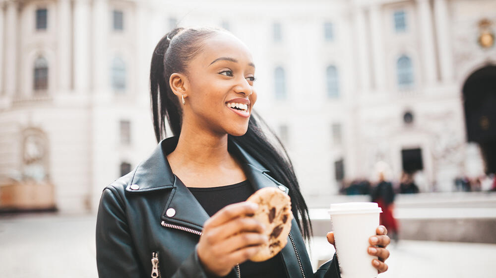 Young woman on a solo trip in Vienna enjoys her breakfast on the go