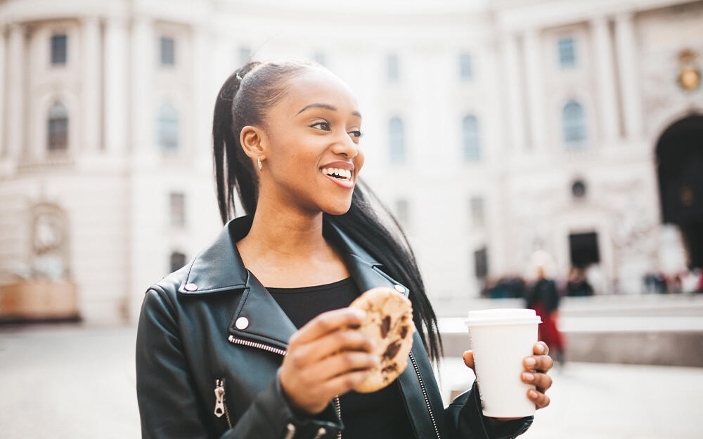 Young woman on a solo trip in Vienna enjoys her breakfast on the go