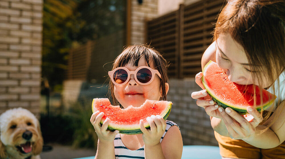 Mutter und Kind mit Sonnenbrille genießen ein erfrischendes Stück Wassermelone