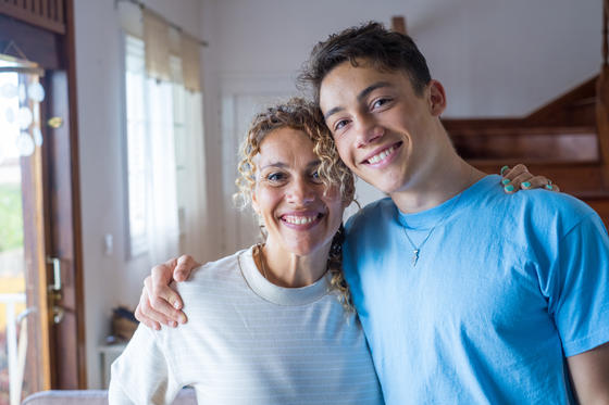  Grateful teenage boy hugging smiling middle-aged mother