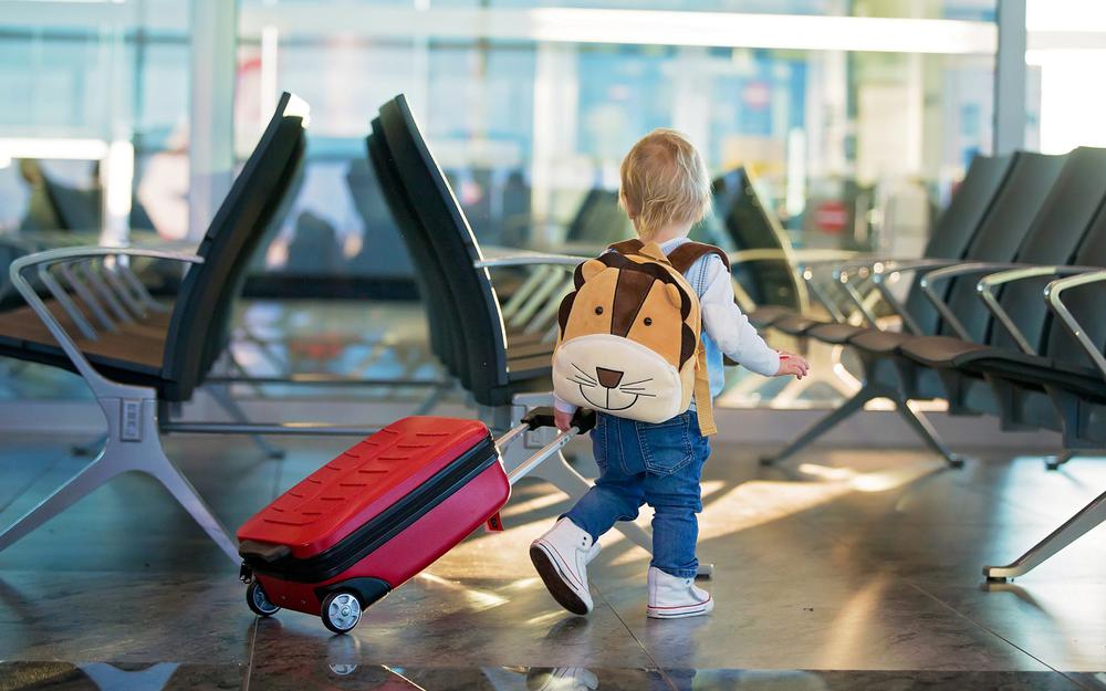 Kleinkind am Flughafen mit Koffer