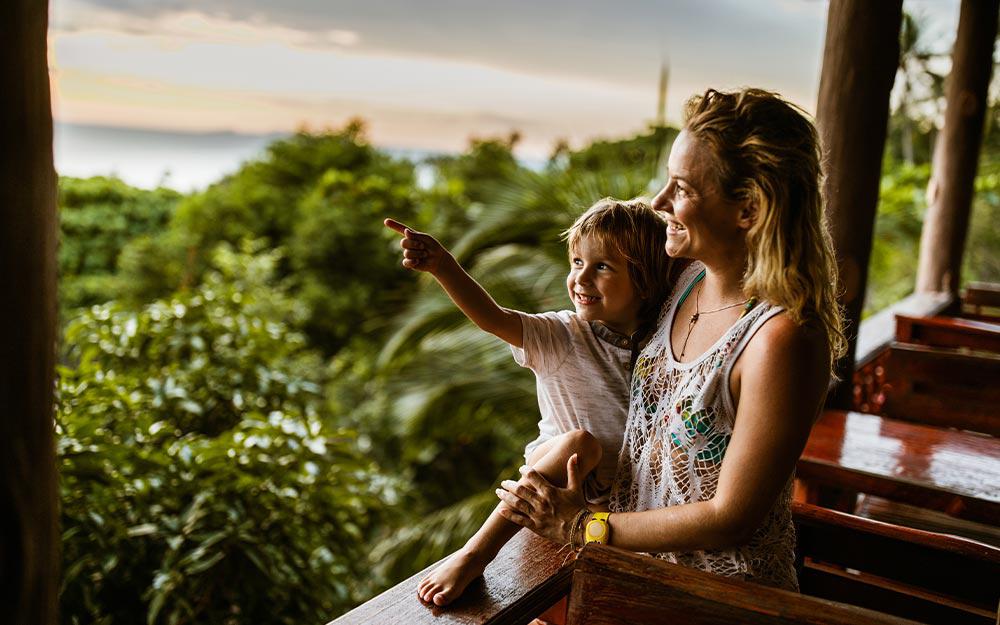 Mutter und Kind genießen den Ausblick von ihrer Unterkunft auf die tropische Natur 