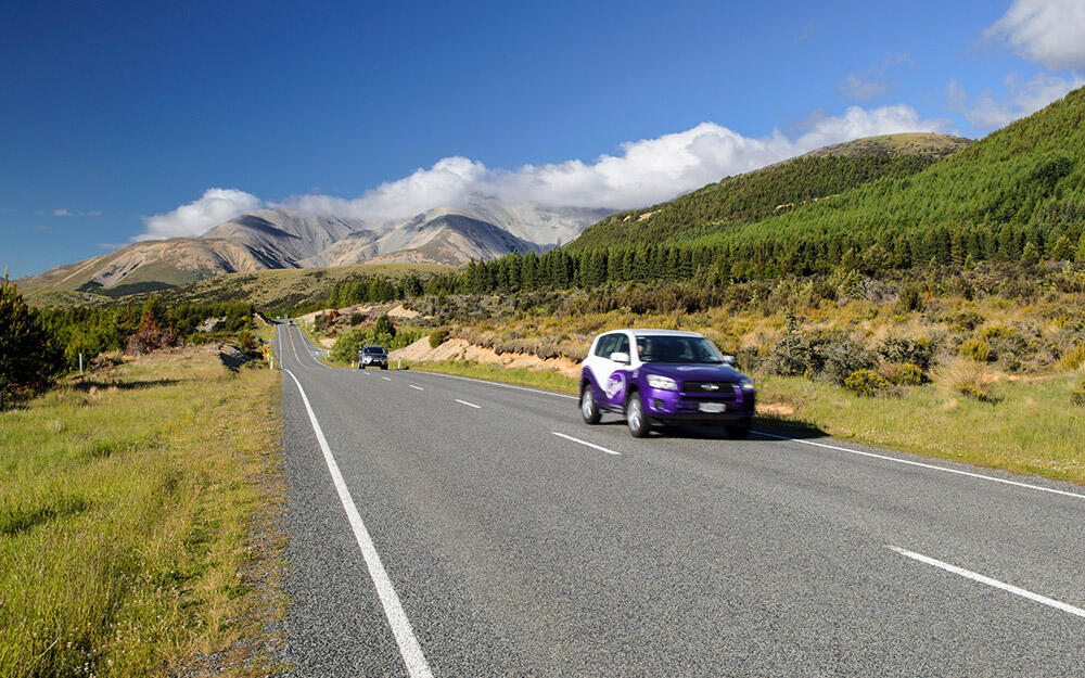 Überlandstraße in Neuseeland mit zwei Autos, die auf der linken Seite fahren