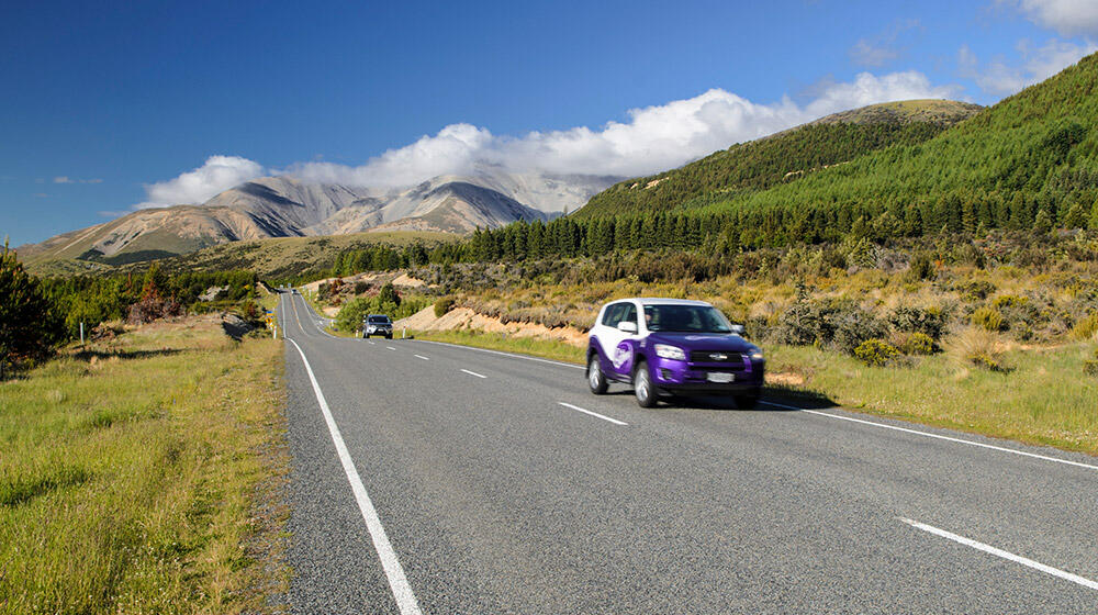 Überlandstraße in Neuseeland mit zwei Autos, die auf der linken Seite fahren