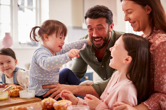 Family playing with daughter with Down Syndrome in kitchen at home