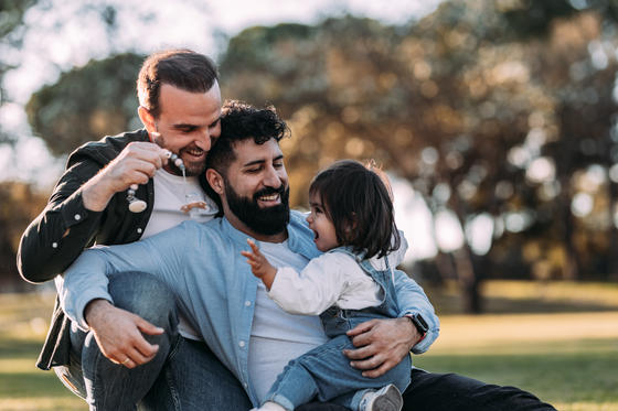 Familie mit zwei Papas spielen mit ihrer Tochter im Park