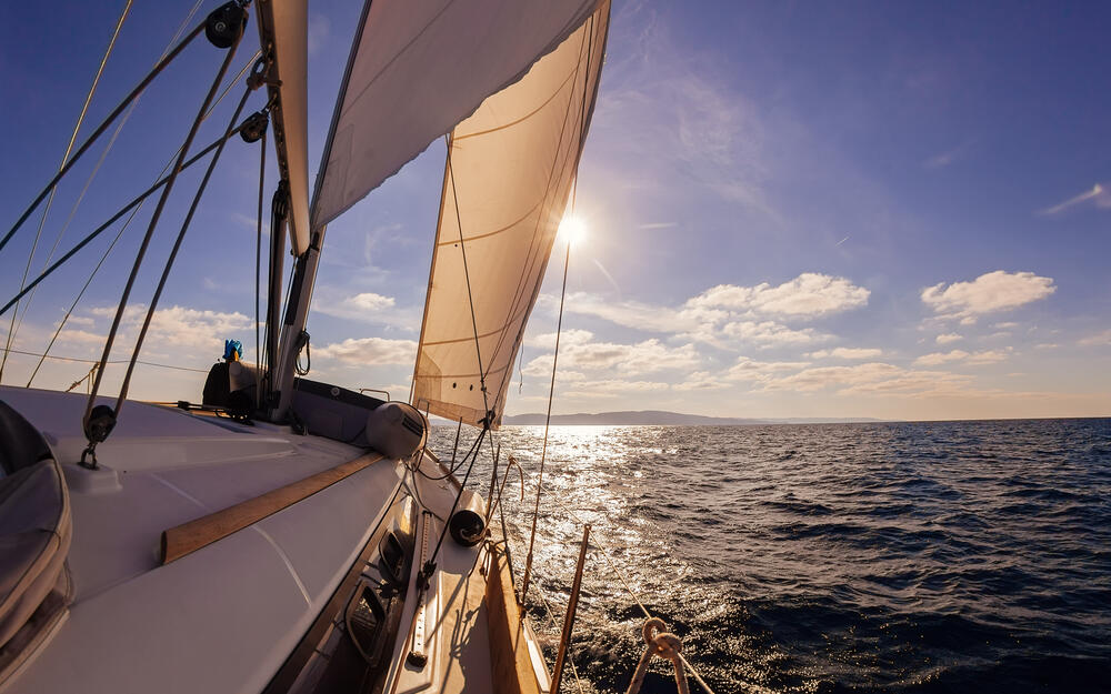 Segelschiff auf hoher ruhiger See fährt Richtung Sonnenuntergang